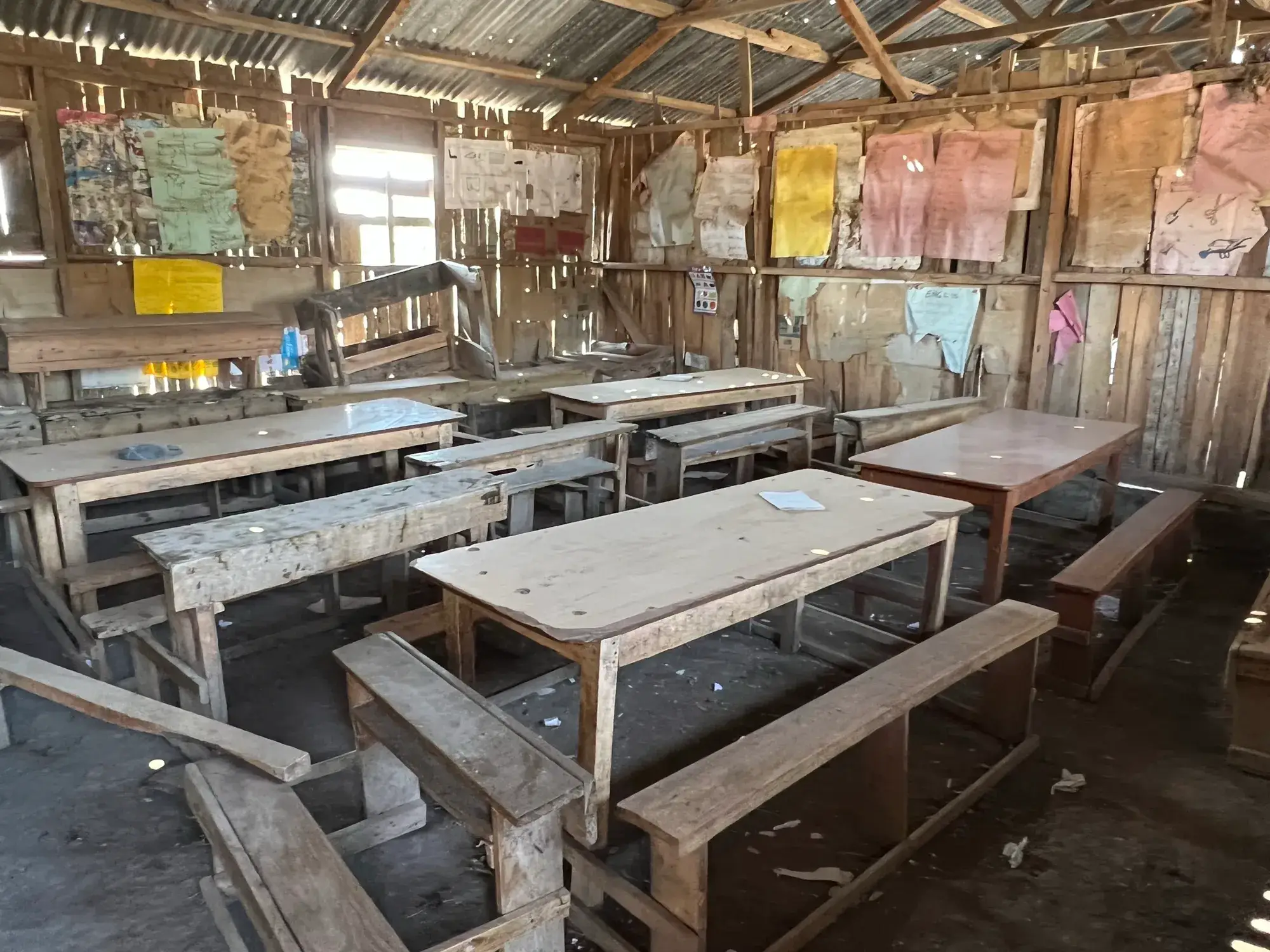 Rows of rough wooden desks under a tin roof
