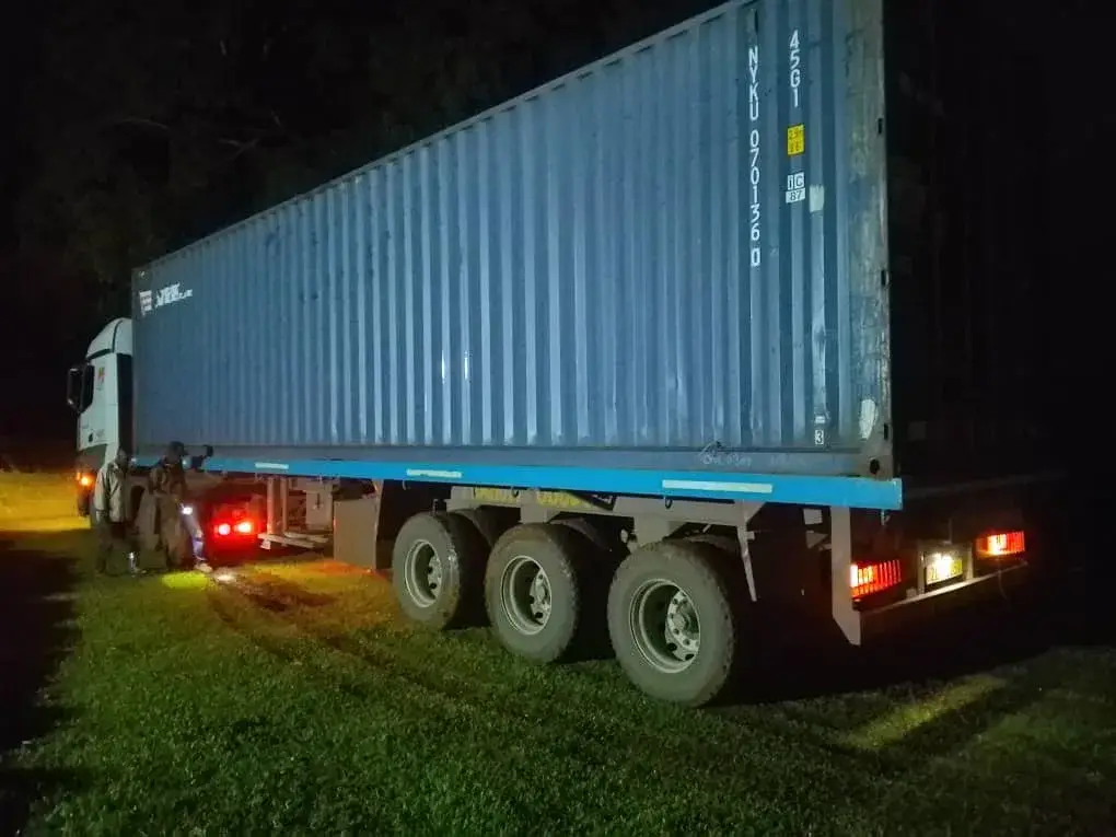 A container truck parked at night, its lights on