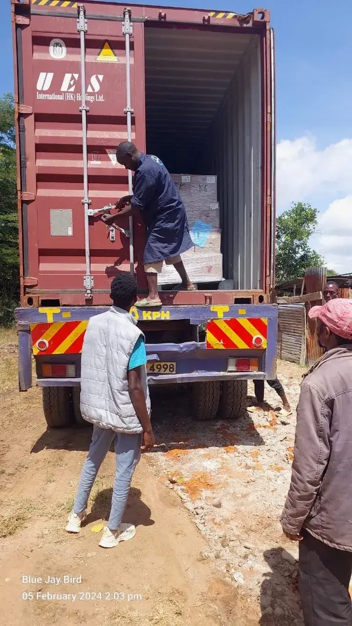 Workers unloading boxes of books from a shipping container on a truck